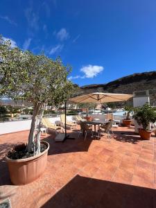 a patio with a table and chairs and an umbrella at COSTA AZUL APARTMENTS - 2B in Puerto de Mogán