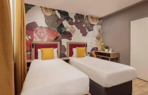 2 camas individuales en una habitación con un mural en Comfort Inn Victoria, en Londres