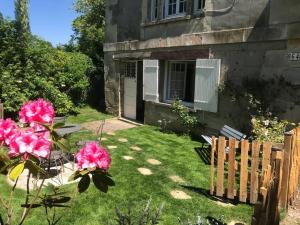 una casa con un patio con flores rosas y una valla en Appartement Le Moulin by La Boîte En Plus, en Senlis