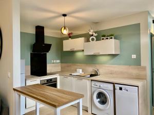 a kitchen with a washing machine and a table at Appt Cosy résidence Palmareda in Tarbes
