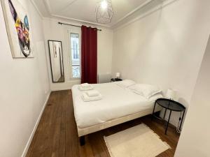 a small white bedroom with a bed and a window at Magnifique Appartement - Mairie 18ème in Paris