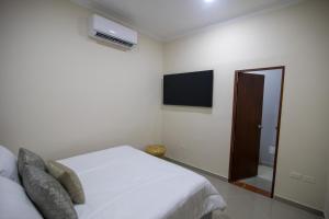 a white bedroom with a bed and a tv at Casa Palmar Cartagena in Cartagena de Indias
