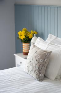 uma cama branca com uma almofada e um vaso de flores em Ty Ffynnon B&B em Tenby