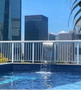 une fontaine dans une piscine avec une ville en arrière-plan dans l'établissement Lapinha 40 Graus Studio, à Rio de Janeiro