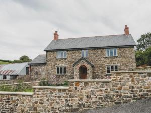 an old stone house with a stone wall at Knowle House in Okehampton