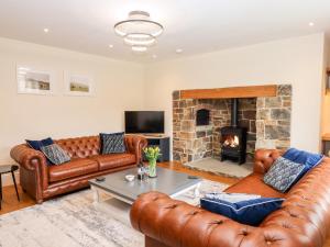a living room with leather couches and a fireplace at Knowle House in Okehampton