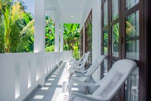 two white chairs on a porch with palm trees at Cliff house in Weligama