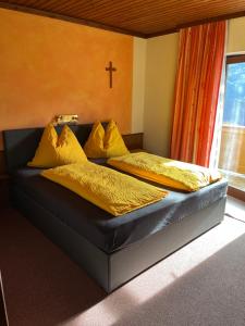 艾希的住宿－Haus Danklmaier/Raudaschl，一间卧室配有两张带黄色枕头的床,墙上有十字架