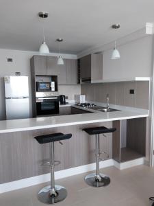 a kitchen with a counter and two bar stools at Departamento vista al mar in Arica