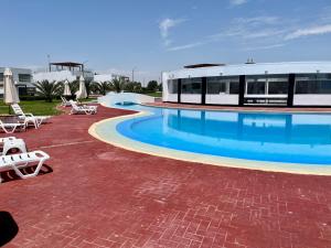 a large swimming pool with chairs and a building at Paracas Paracas! 2do Piso Vista al Mar 140 Metros - Sotavento 201 T6 in Paracas