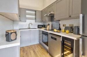 una cucina con armadietti bianchi ed elettrodomestici in acciaio inossidabile di Waterfoot Park a Pooley Bridge