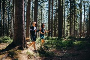 un hombre y una mujer caminando por un bosque en Czarny Kamień Resort & SPA, en Szklarska Poręba