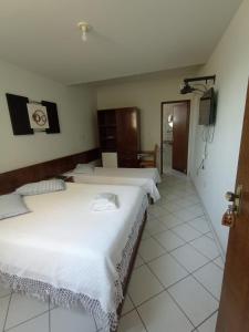 a bedroom with two beds and a door to another room at HOTEL DONA JOSA in Carmo do Cajuru