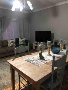 uma sala de estar com uma mesa de madeira e um sofá em House Fynbos, 4 Bedroom house em Bloemfontein