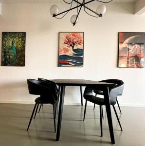 a dining table and chairs in a room with paintings at Chic Atelier with Breathtaking Waterfront in Copenhagen