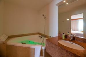 een badkamer met een bad, een wastafel en een spiegel bij CERISE Bordeaux Mérignac Aéroport in Mérignac