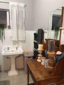 baño con lavabo, mesa y espejo en House Fynbos, 4 Bedroom house en Bloemfontein