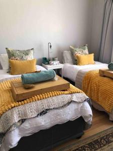 a bedroom with two beds with yellow pillows at House Fynbos, 4 Bedroom house in Bloemfontein
