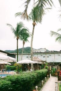 a resort with palm trees in front of a building at Lua Chales in Maresias