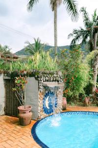 a swimming pool in a garden with a fountain at Lua Chales in Maresias