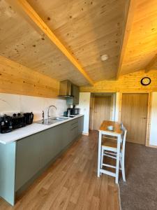 een keuken met houten plafonds en een houten tafel bij Glenariff Forest Larch Cabin in Glenariff