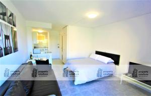 Un pequeño dormitorio con una cama y una cocina. en 426 Estudio en Minerva Apartamentos - Vista al jardín - Piscina y Playa, en Benalmádena