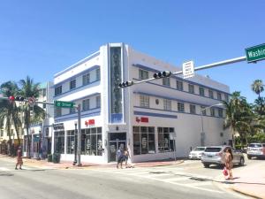 a white building on a street corner with people crossing the street at Best location in MB - 2 min to beach & Ocean Dr in Miami Beach