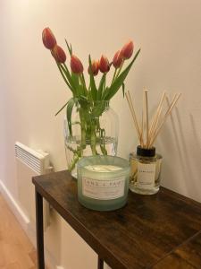 a vase of flowers on a table with a candle at Spacious Mews Apartment, Clapham in London