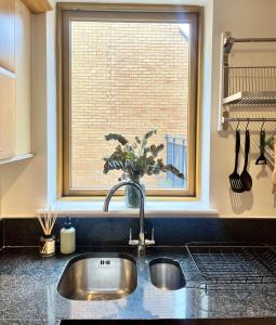 a kitchen sink with a vase of flowers in a window at Spacious Mews Apartment, Clapham in London