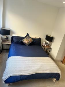 a bedroom with a bed with blue sheets and two lamps at Spacious Mews Apartment, Clapham in London