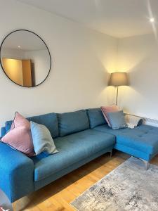 Sofá azul en la sala de estar con espejo en Spacious Mews Apartment, Clapham, en Londres