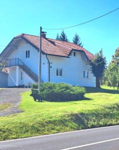 a large white house on a grassy field at Apartman Tina in Rakovica