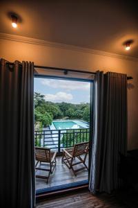 een kamer met een balkon met uitzicht op een zwembad bij Covanro Sigiriya - Brand New Luxury Hotel in Sigiriya