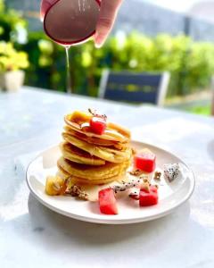 a plate of pancakes with syrup and fruit on a table at Namu Hotel in Pai