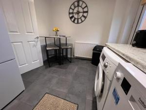 eine Küche mit einem Tisch und einer Uhr an der Wand in der Unterkunft CONTRACTORS OR FAMILY HOUSE M1 Nottingham - IKEA RETAIL PARK - SWINDON CLOSE - 2 Bed Home with Driveway, private garden, sleeps 4 - TV'S in all rooms in Giltbrook