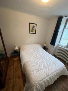 1 dormitorio con 1 cama blanca grande y 2 lámparas en maison de campagne, en Saint-Martin-Château