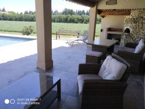 d'une terrasse avec des chaises en osier, une table et une cheminée. dans l'établissement Le Mas des Calus Chambres d'hôtes, à LʼIsle-sur-la-Sorgue