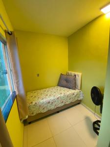 a small room with a bed in a yellow wall at Residencial Sítio Paraíso in Itacaré