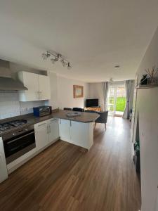 a kitchen with white cabinets and a wooden floor at Buckthorn House - James Cook Hospital in Middlesbrough