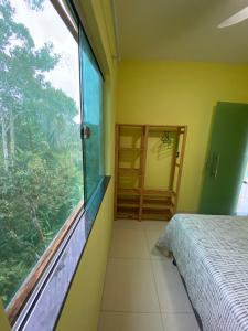a bedroom with a bed and a large window at Residencial Sítio Paraíso in Itacaré