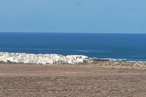 un groupe de bâtiments blancs au-dessus d'une plage dans l'établissement Sabbia Suites Barlovento, à Famara