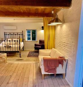 ein Wohnzimmer mit einem Sofa und einem Bett in der Unterkunft Den gamle skomager hytte ved søen in Gråsten