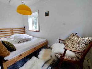ein Schlafzimmer mit einem Bett, einem Stuhl und einem Fenster in der Unterkunft Den gamle skomager hytte ved søen in Gråsten