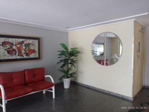 a living room with a red couch and a mirror at PRIME Beach do Forte, Polo Gourmet, e Praia do Forte a Pé in Cabo Frio
