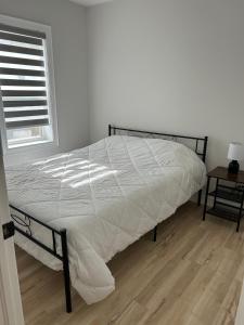 a bed with a white comforter in a bedroom at Brand New Home in Hamilton in Hamilton