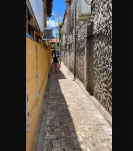 a narrow alley with two people walking down it at Suíte, Bem localizado em Morro de São Paulo Ba in Cairu