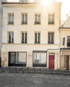biały budynek z oknami i czerwonymi drzwiami w obiekcie 1 bedroomed Apartment Repos w Paryżu