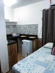 a room with a bed and a desk with a refrigerator at Suíte, Bem localizado em Morro de São Paulo Ba in Cayru