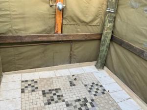 a bathroom with a tiled floor and a wall with a tiled at Lorato Lodge and Camping in Muchenje