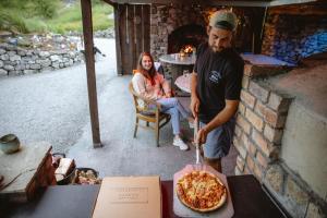 Um homem está a pôr uma pizza no forno. em Mayo Glamping em Castlebar